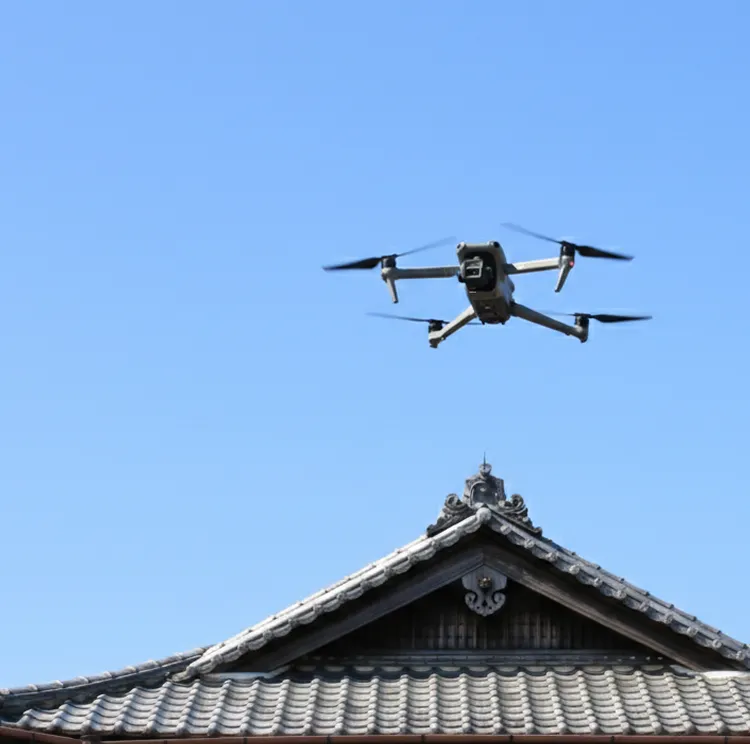 ドローンが住宅屋根を上空から撮影している様子